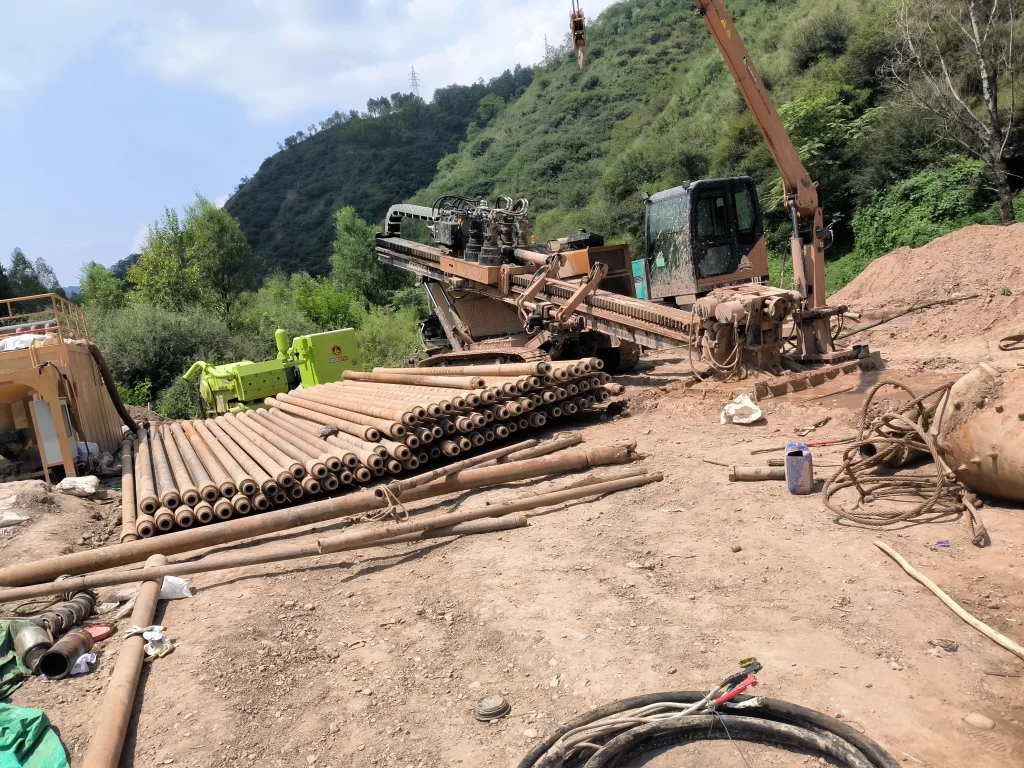 HDD trenchless drilling rig and drill rods at a hillside construction site